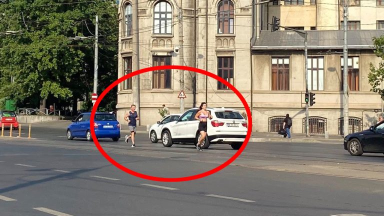 Două persoane alergând pe trecerea de pietoni într-un oraș aglomerat, cu mașini și clădiri în fundal