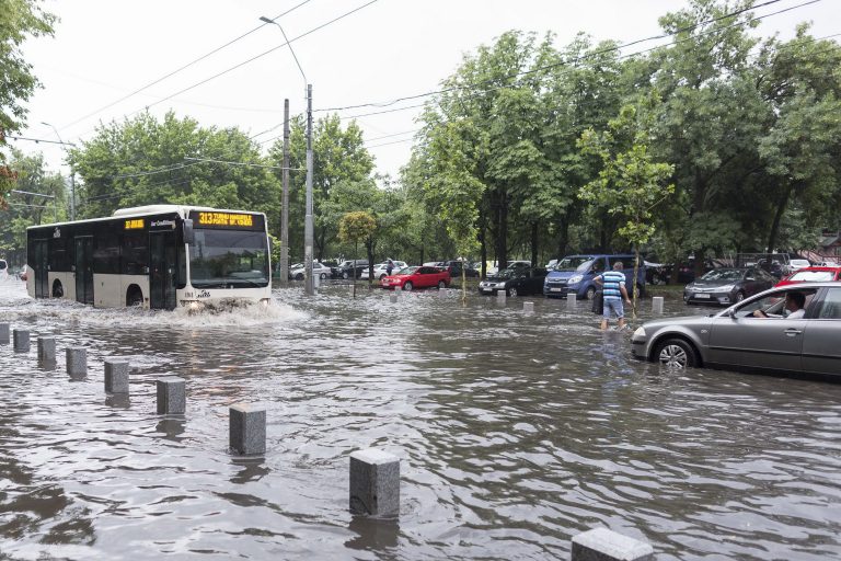Autobuz și mașini blocate pe o stradă inundată după o ploaie torențială într-un oraș