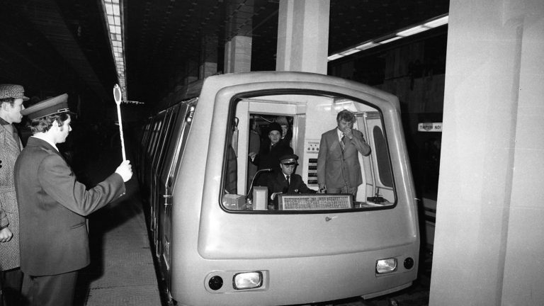 Primul tren de metrou din București la inaugurarea oficială în anii 1970, cu personal feroviar și pasageri în stație.