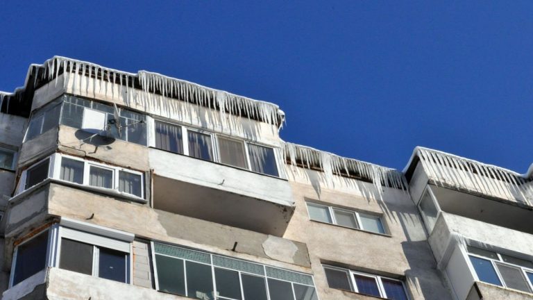 Pericol de țurțuri la marginea acoperișului unui bloc de locuințe