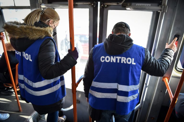 Doi controlori STB purtând veste albastre cu inscripția CONTROL, aflați într-un mijloc de transport în comun din București.
