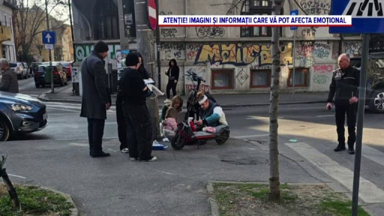 Persoane acordând primul ajutor unei victime căzute lângă o trotinetă electrică pe trotuar, într-o zonă urbană
