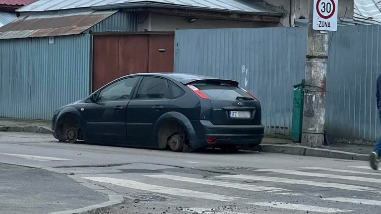 Mașină Ford Focus neagră lăsată pe discuri după ce i-au fost furate toate roțile pe o stradă din Buzău, România