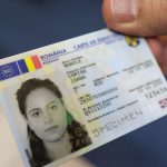 Carte de identitate electronică românească ținută în mână, cu fotografie și date personale vizibile