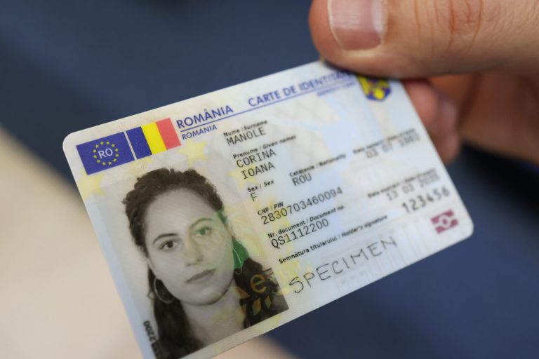 Carte de identitate electronică românească ținută în mână, cu fotografie și date personale vizibile