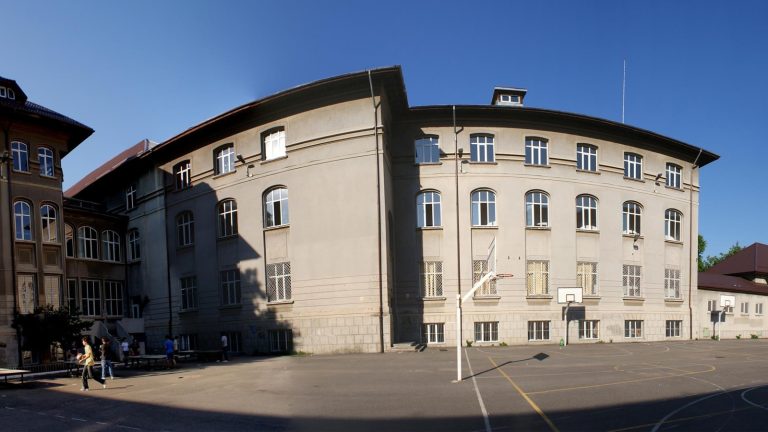 Clădirea Colegiului Național de Informatică Tudor Vianu, cu teren de baschet în curtea școlii, într-o zi senină de vară, București.