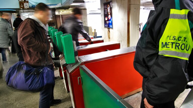 Agent de pază Metrorex supraveghează accesul călătorilor la porțile de validare într-o stație de metrou aglomerată din București.