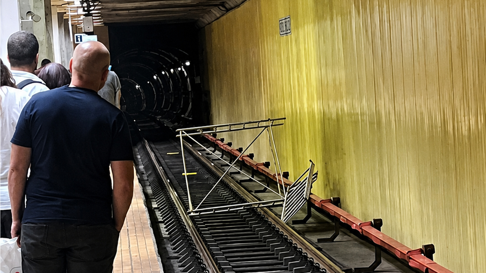 Obiect metalic căzut pe șinele de metrou într-o stație din București, în timp ce călătorii așteaptă pe peron. Incident care poate afecta circulația trenurilor de metrou.