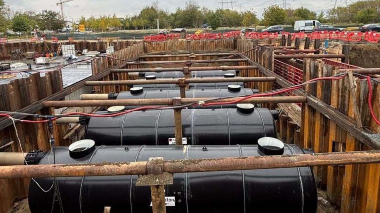 Rezervoare mari de stocare subterană din plastic negru montate într-o excavație securizată pe un șantier de construcții industriale.