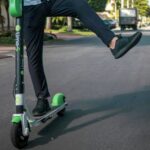 Persoană care merge pe o trotinetă electrică Lime pe o stradă urbană