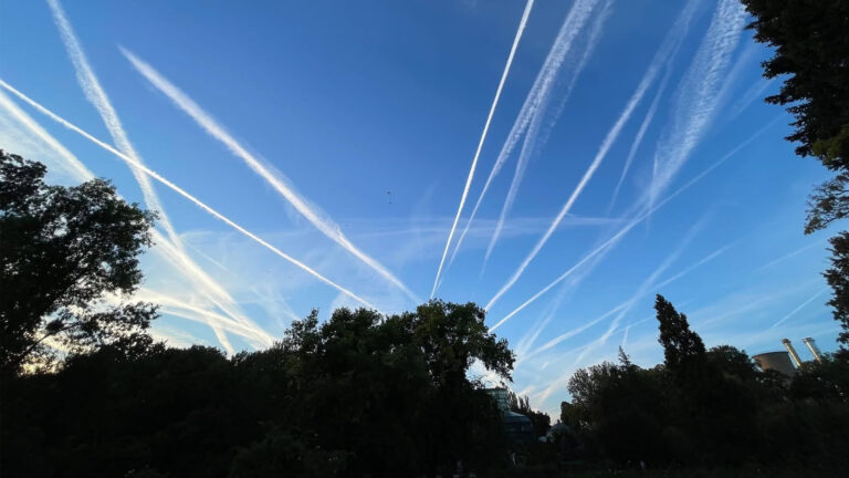 Dâre de condensare persistente lăsate de avioane pe cerul albastru al Bucureștiului